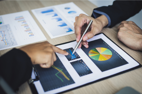 People marking and pointing on a board with graphs